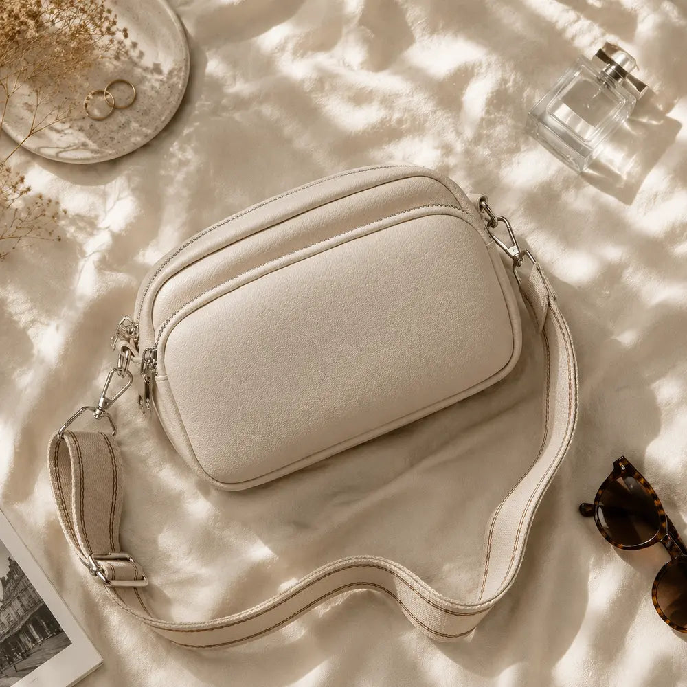 Petit sac à main crème Hermine, flatlay premium sur satin champagne