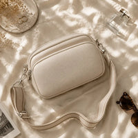 Petit sac à main crème Hermine, flatlay premium sur satin champagne