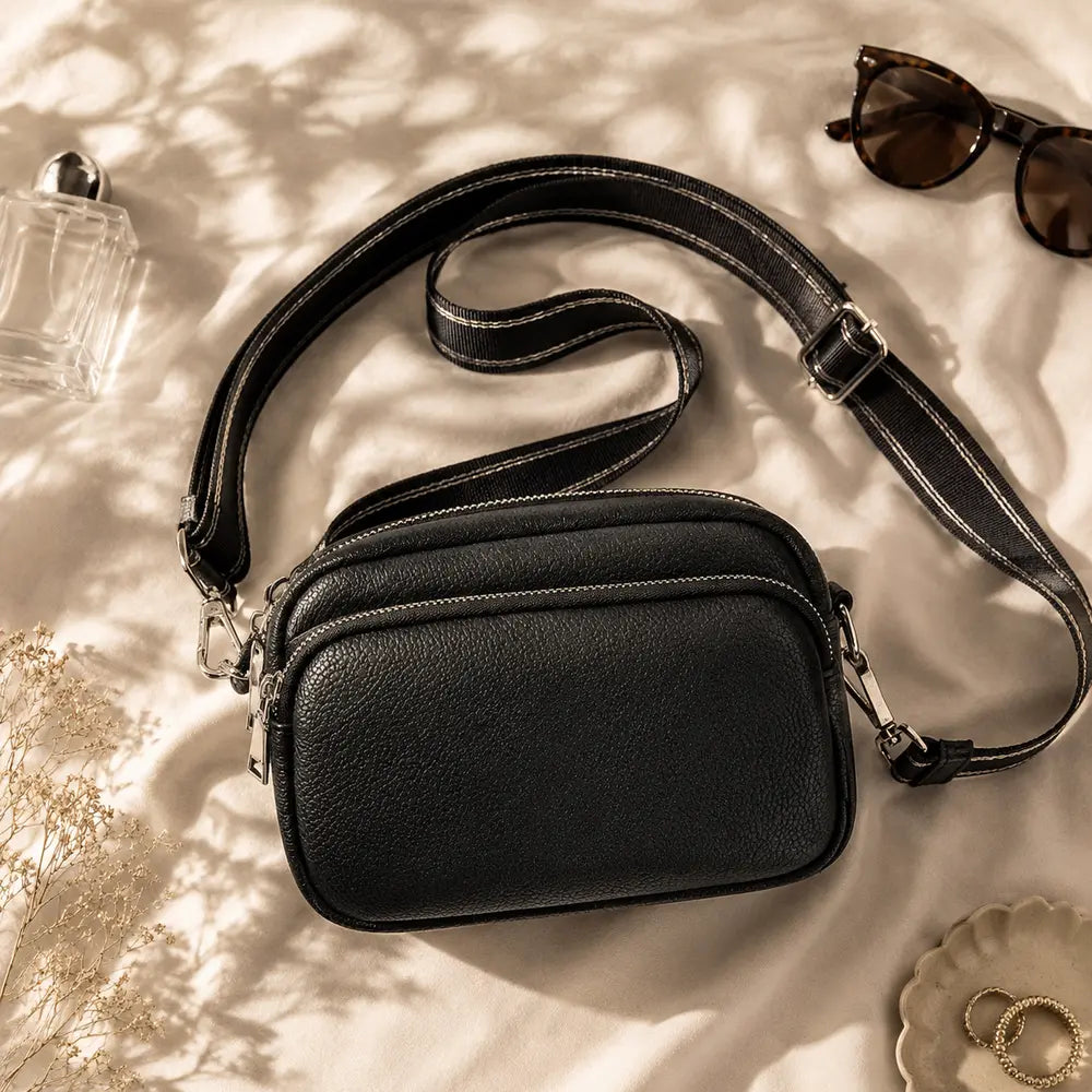 Petit sac à main noir Hermine, flatlay premium sur satin champagne
