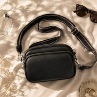 Petit sac à main noir Hermine, flatlay premium sur satin champagne