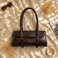 Sac à main marron foncé Nine, flatlay premium sur satin champagne
